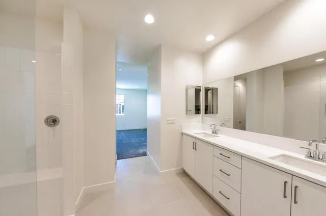 a spacious bathroom with a double vanity sink a mirror and shower