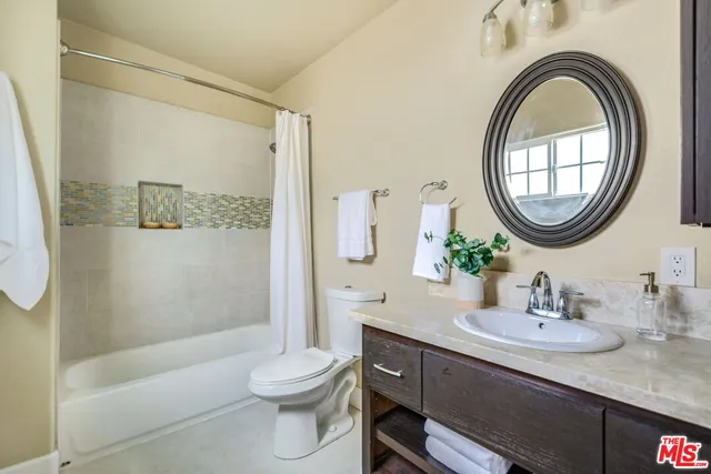 a bathroom with a granite countertop toilet a sink and a mirror