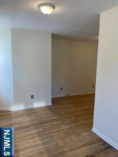 a view of an empty room with wooden floor and entryway