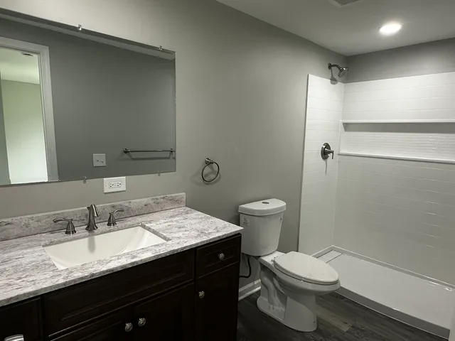 a bathroom with a granite countertop sink toilet and shower