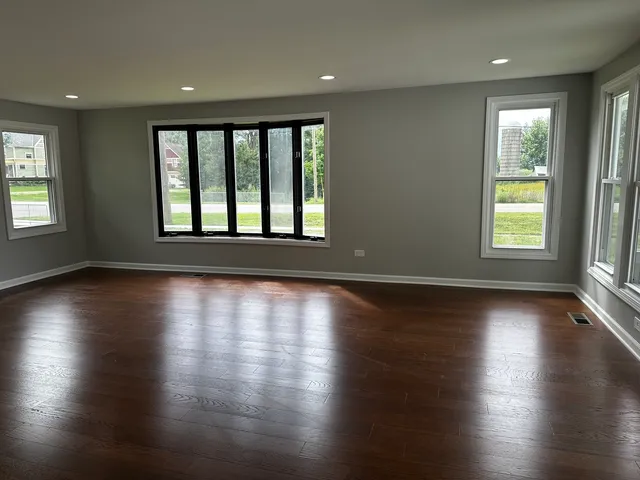 an empty room with wooden floor and windows