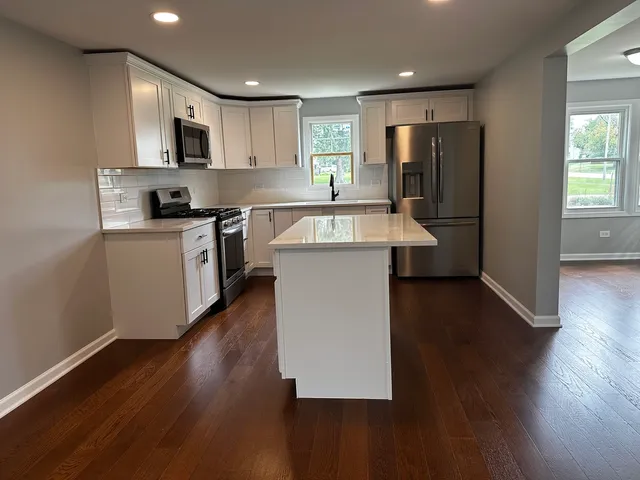 a kitchen with kitchen island granite countertop wooden floors and stainless steel appliances