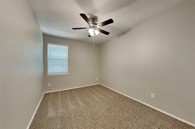 an empty room with window and ceiling fan