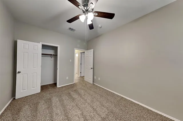 an empty room with closet and a chandelier fan