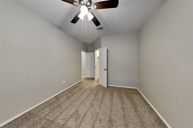 an empty room with a ceiling fan and carpet