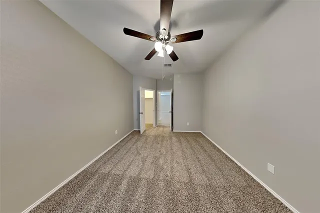 a view of an empty room and chandelier fan