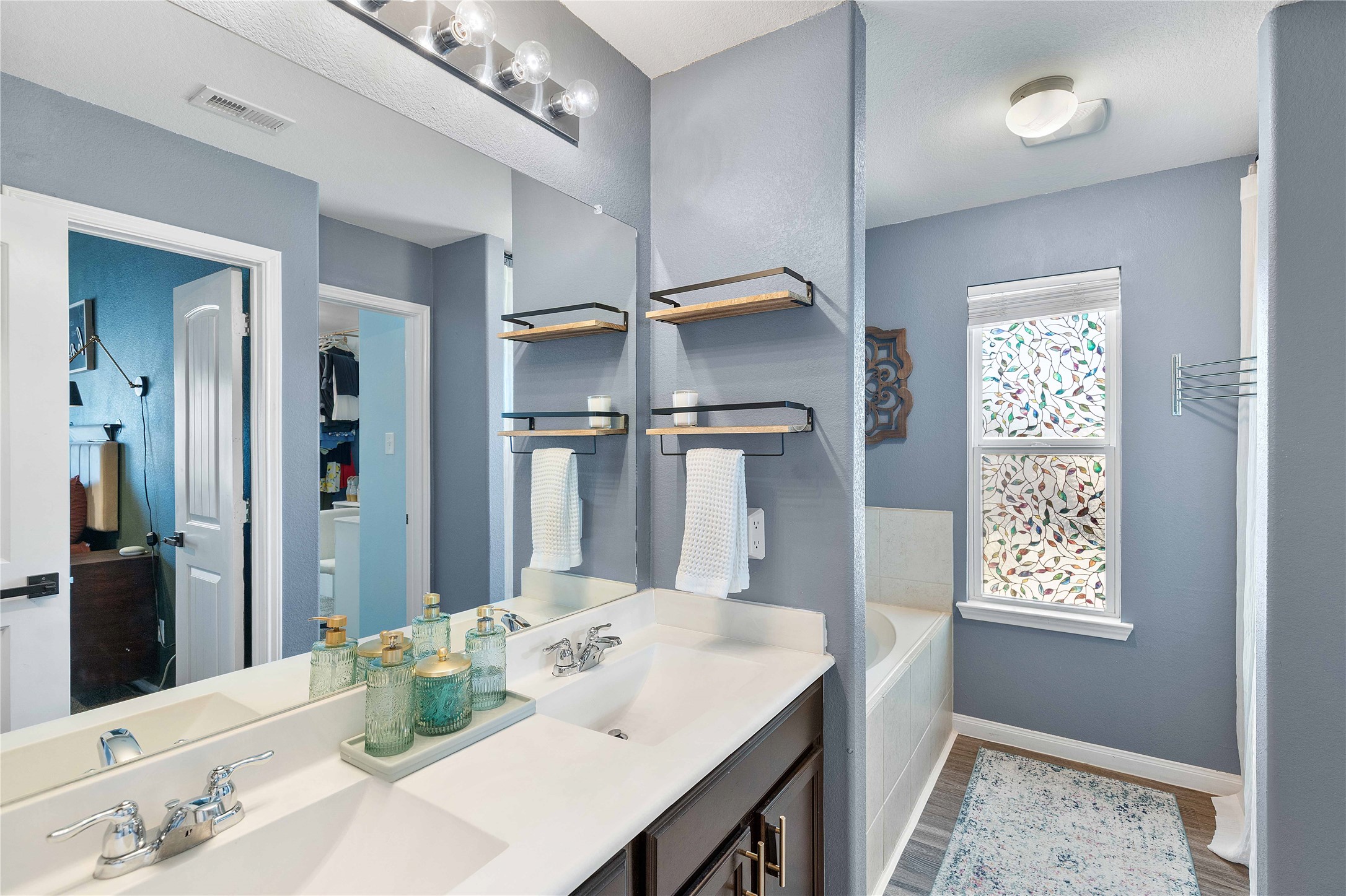 18623 Jerrara Stream Lane Katy, TX 77449 - Photo 23 of 46 The primary bathroom has double sinks, shelving storage, a glass shower, AND a private soaking tub. Perfect for storage and relaxation.