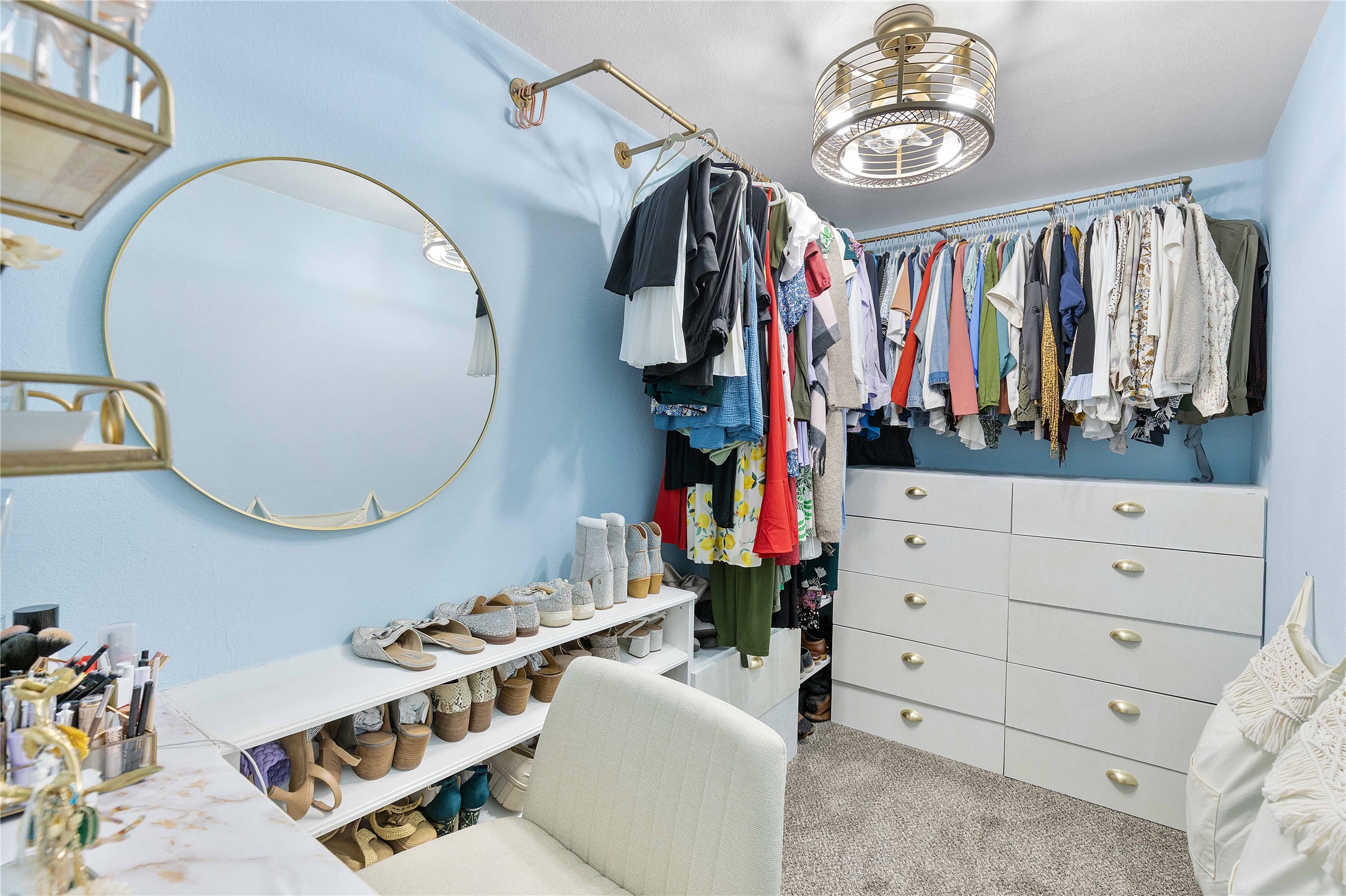 18623 Jerrara Stream Lane Katy, TX 77449 - Photo 26 of 46 Luxury touches and well-thought out space are two phrases to describe this primary bedroom closet. Custom shelving and drawers have been added for storage all in one place. Gold accents including luxury clothing rods and a fan-delier make this the perfect glam room/closet.
