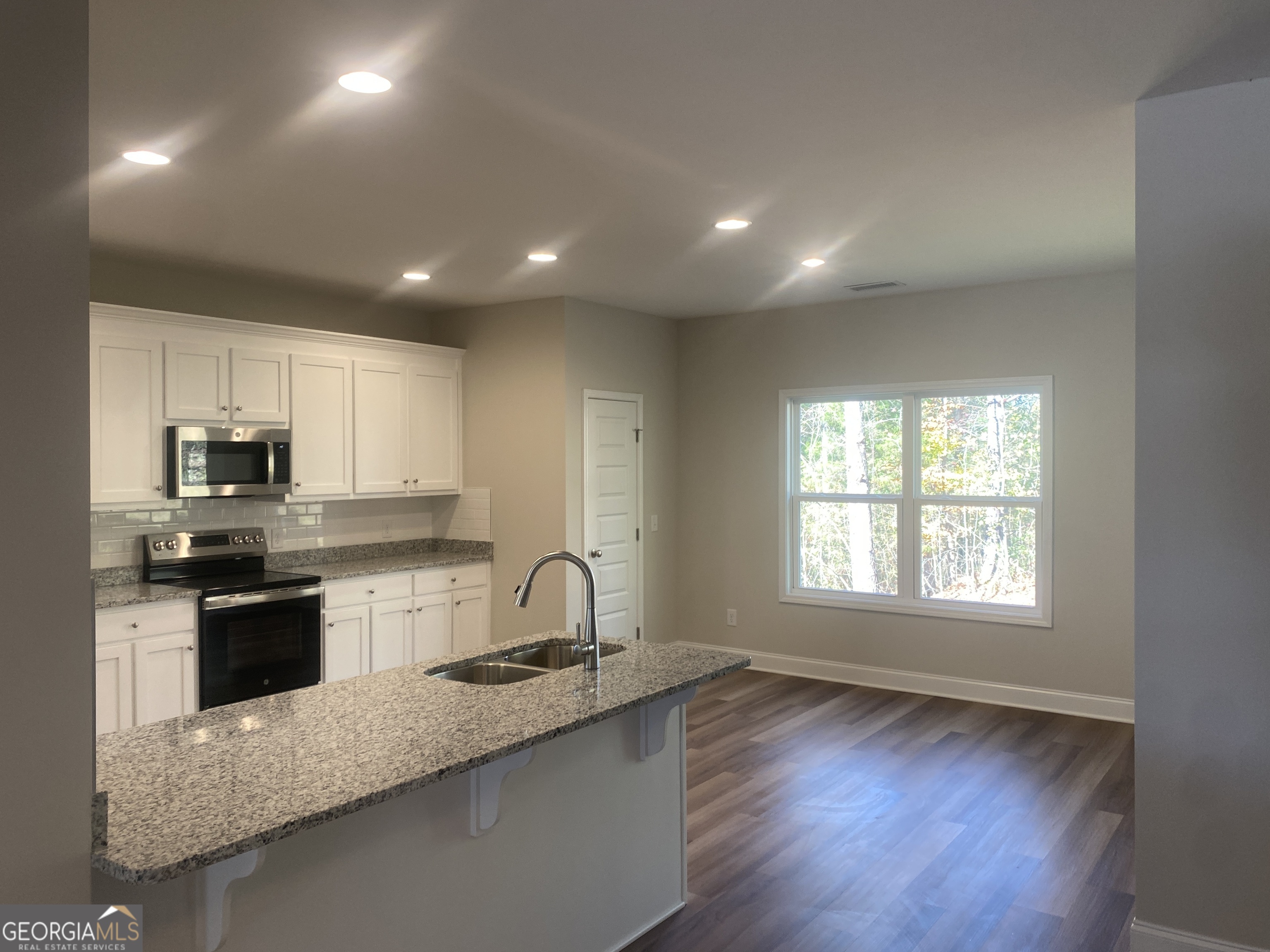 296 Delightful Way, Unit 22 Winder, GA 30680 - Photo 4 of 13 a large kitchen with stainless steel appliances granite countertop a sink a stove a refrigerator counter space and wooden floor