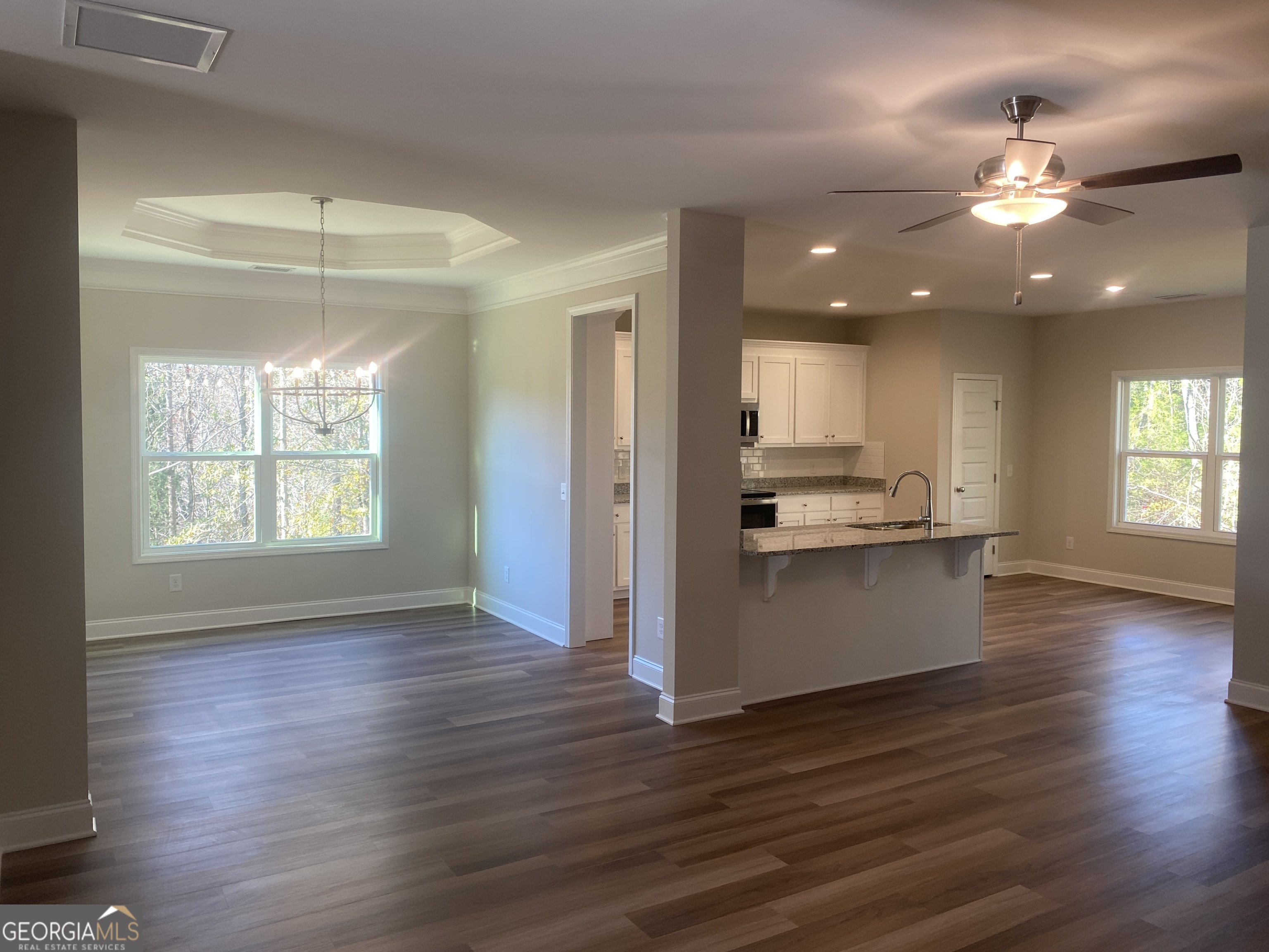 296 Delightful Way, Unit 22 Winder, GA 30680 - Photo 7 of 13 a view of a kitchen and an empty room with wooden floor and a kitchen