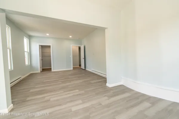 an empty room with wooden floor and windows