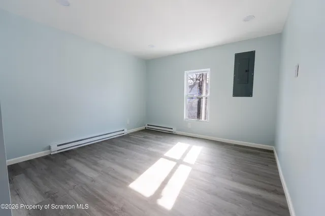 an empty room with wooden floor and window