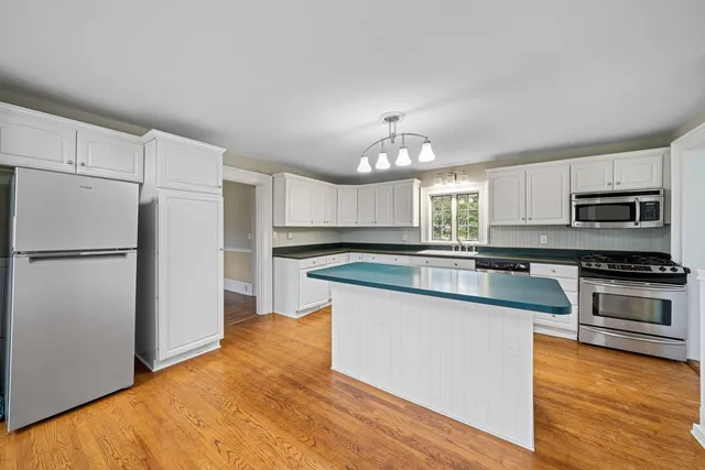 a large kitchen with stainless steel appliances granite countertop a stove and a sink with cabinets