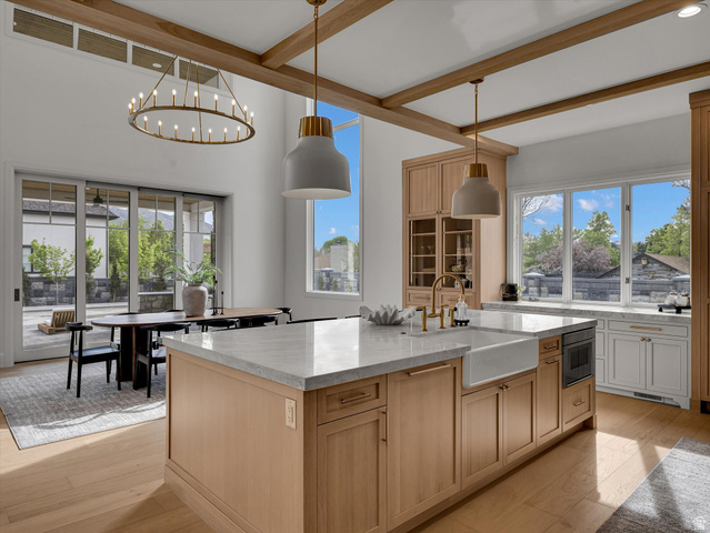 13216 Telemark Lane Draper, UT 84020 - Photo 9 of 41 Kitchen featuring light stone countertops, a kitchen island with sink, beamed ceiling, light wood-style floors, and two tone cabinetry