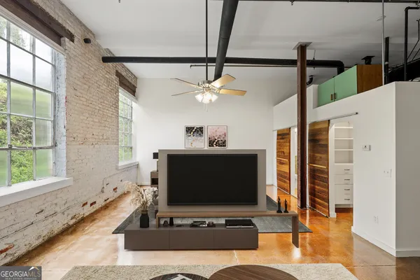 a living room with furniture a flat screen tv and a large window