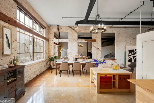 a kitchen with stainless steel appliances kitchen island granite countertop a table chairs in it and white cabinets