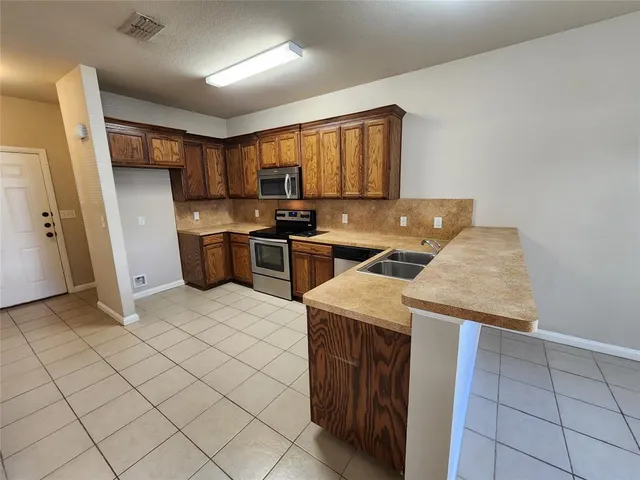 a kitchen with stainless steel appliances granite countertop a sink stove refrigerator and cabinets