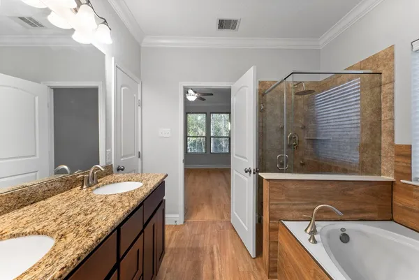 a bathroom with a granite countertop double vanity sink and mirror with bathtub