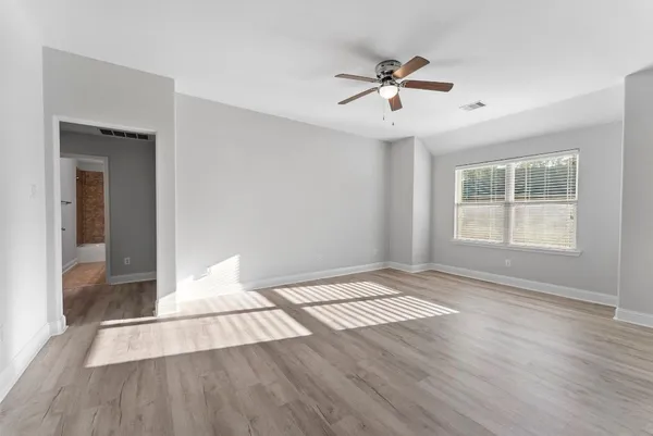 a view of an empty room with wooden floor and a window