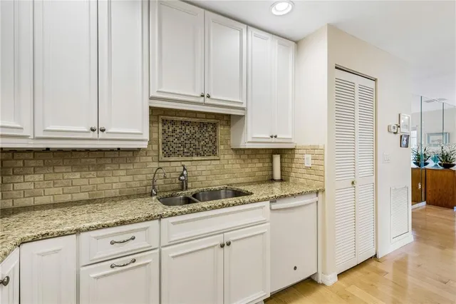 a kitchen with granite countertop white cabinets and stainless steel appliances