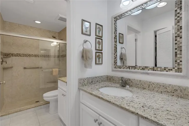 a bathroom with a granite countertop sink a mirror and a toilet