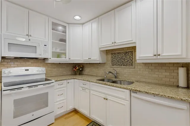 a kitchen with granite countertop white cabinets and stainless steel appliances