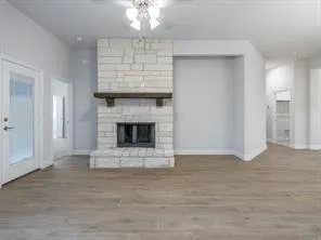 a view of an empty room with wooden floor fireplace and a window