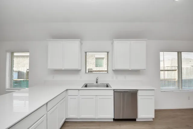 a kitchen with white cabinets and sink