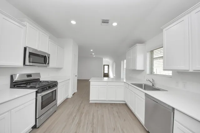 a kitchen with granite countertop a sink wooden floor and stainless steel appliances
