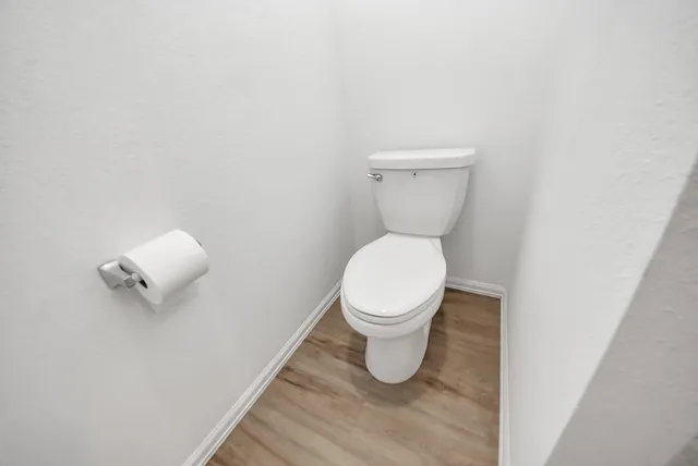 a white toilet sitting next to a white wall