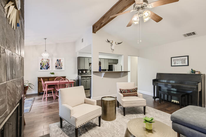 5107 Leralynn Street, Unit 304 Austin, TX 78751 - Photo 23 of 28 Living area with wood finished floors, ceiling fan, a tiled fireplace, baseboards, and a chandelier