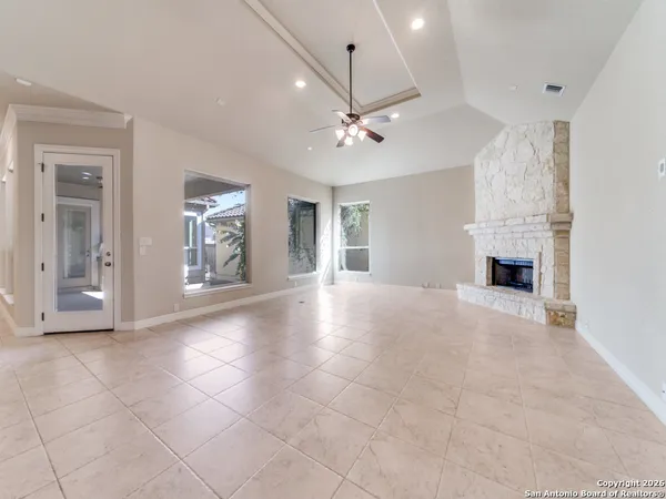 a view of an empty room with chandelier fan and fire place