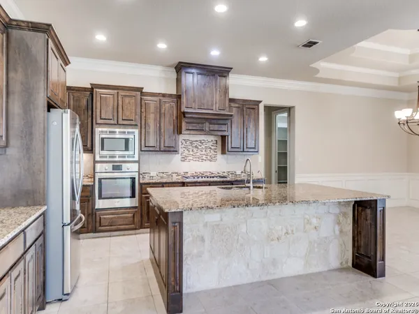a kitchen with stainless steel appliances granite countertop a sink dishwasher and a dining table with a large kitchen island