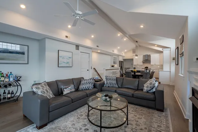 a living room with furniture kitchen view and a chandelier