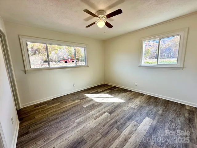 a view of empty room with wooden floor and fan