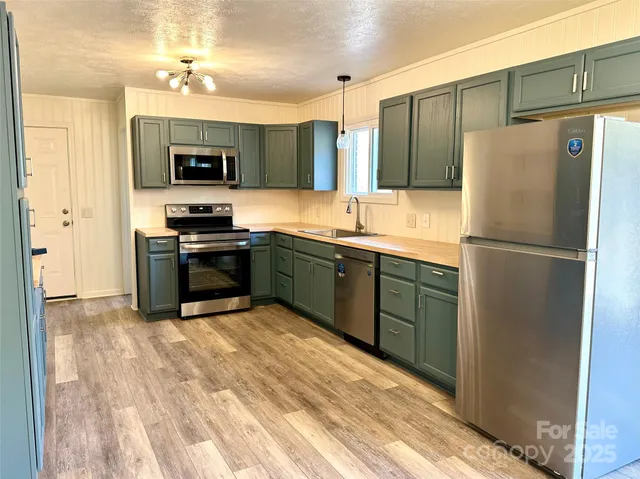 a kitchen with stainless steel appliances granite countertop a refrigerator a sink and a stove