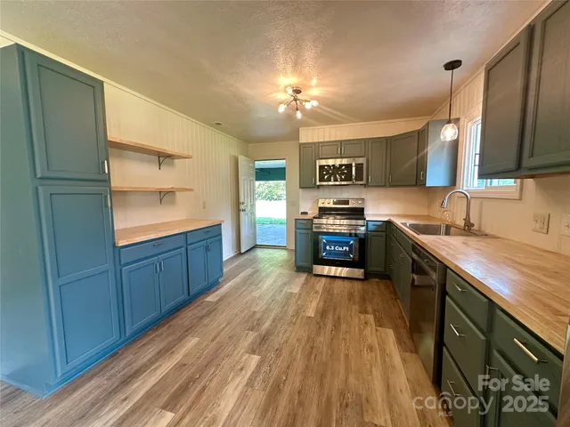 a kitchen with stainless steel appliances granite countertop a sink a stove and a wooden floors