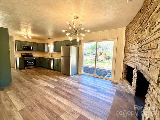 a kitchen with stainless steel appliances kitchen island granite countertop a refrigerator oven a sink with dishwasher and cabinets with wooden floor