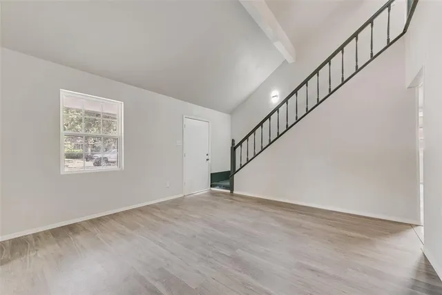 a view of an empty room with wooden floor and stairs