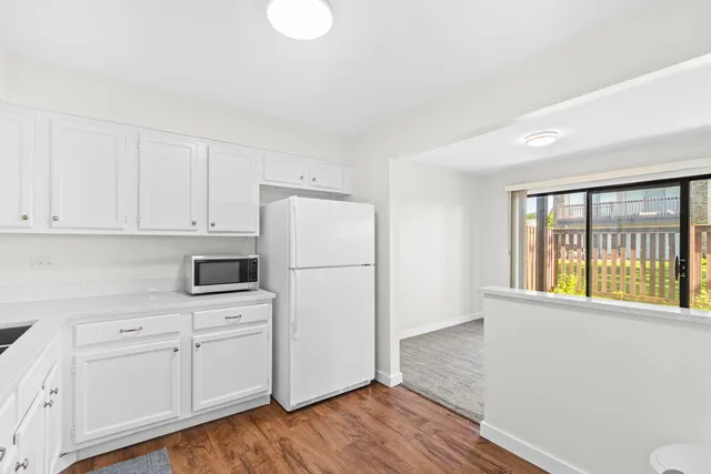 a kitchen with white cabinets and wooden floor