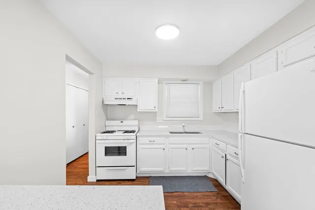 a kitchen with white cabinets and white appliances