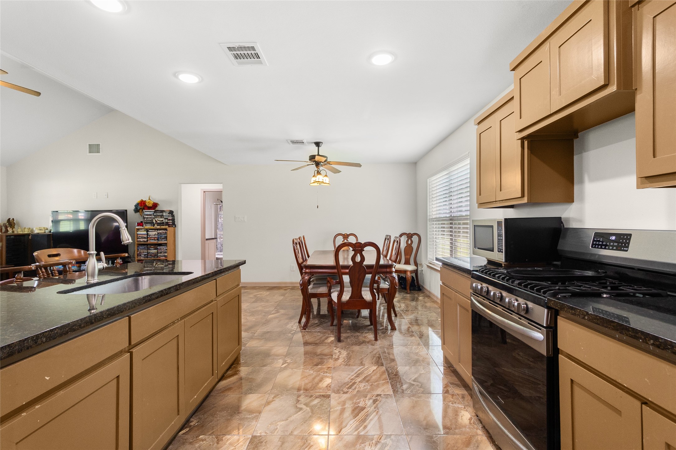 1545 County Road 2145 Cleveland, TX 77327 - Photo 11 of 22 a kitchen with stainless steel appliances granite countertop a stove top oven a sink a dining table and chairs with wooden floor