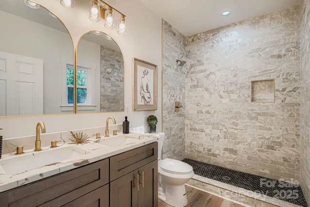 a bathroom with a granite countertop toilet a sink a mirror a window and vanity