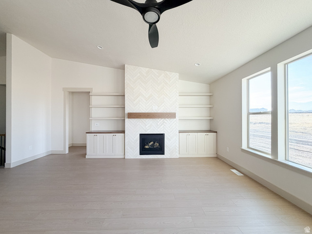 533 West S Temple Street, Unit 309 Tooele, UT 84074 - Photo 7 of 24 Unfurnished living room with light wood finished floors, a fireplace, and ceiling fan