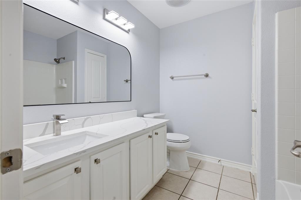 10001 Thurman Road Fort Worth, TX 76244 - Photo 24 of 40 Bathroom featuring a white double vanity with an integrated sink, a large frameless mirror, and a three-light vanity fixture