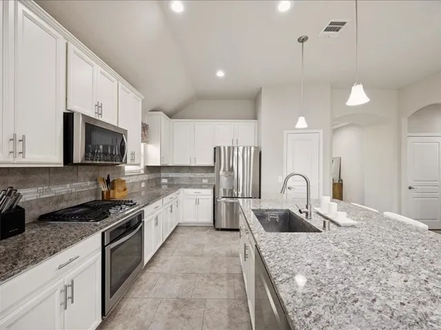 a kitchen with granite countertop a sink a stove and cabinets