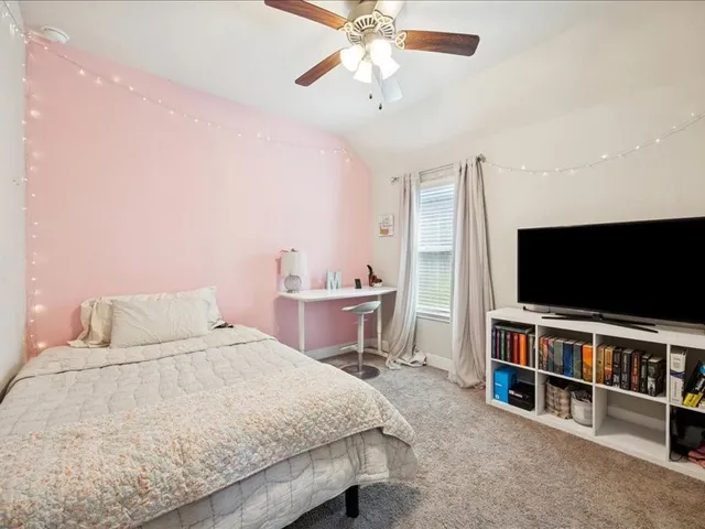 a bedroom with a bed and a flat tv screen on dresser
