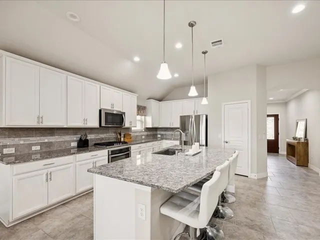 a kitchen with stainless steel appliances granite countertop a sink stove and cabinets