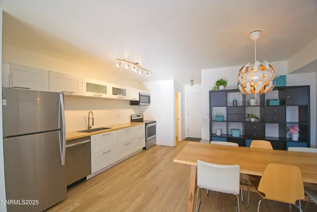 a kitchen with granite countertop a refrigerator a stove a sink dishwasher a dining table and chairs with wooden floor