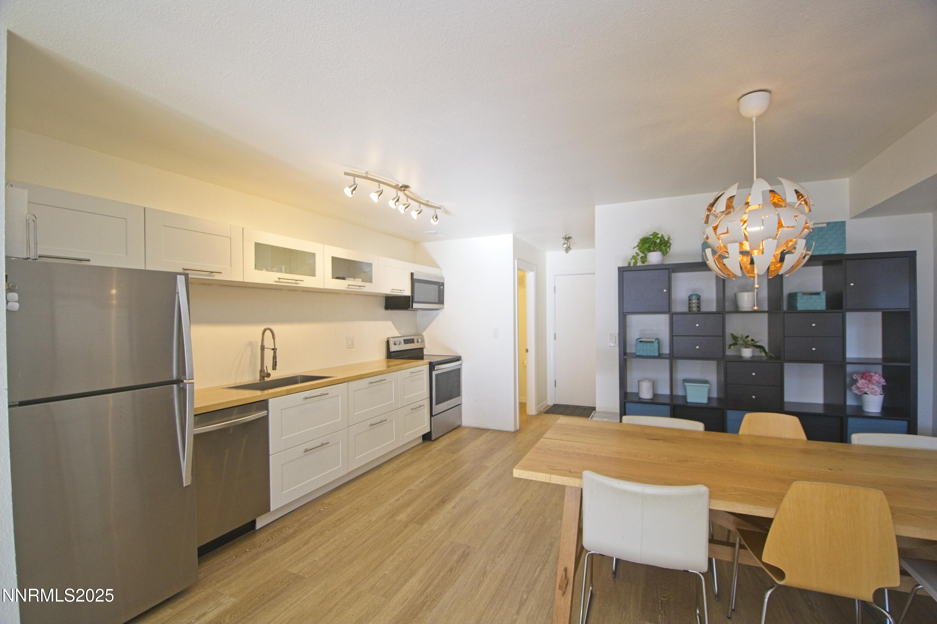 125 Mary Street, Unit A Reno, NV 89509 - Photo 7 of 22 a kitchen with granite countertop a refrigerator a stove a sink dishwasher a dining table and chairs with wooden floor